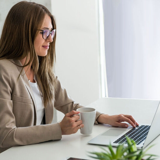 Digital Mailroom Solution of a young woman working on laptop with mug